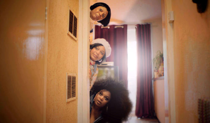 Three women peeking round a door