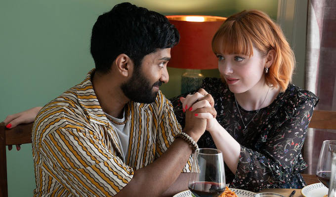 Young man and woman, Evie, holding hands over kitchen table