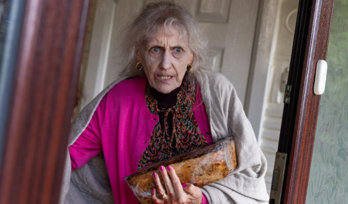 Bedraggled looking Anita Dobson carrying a loaf of bread