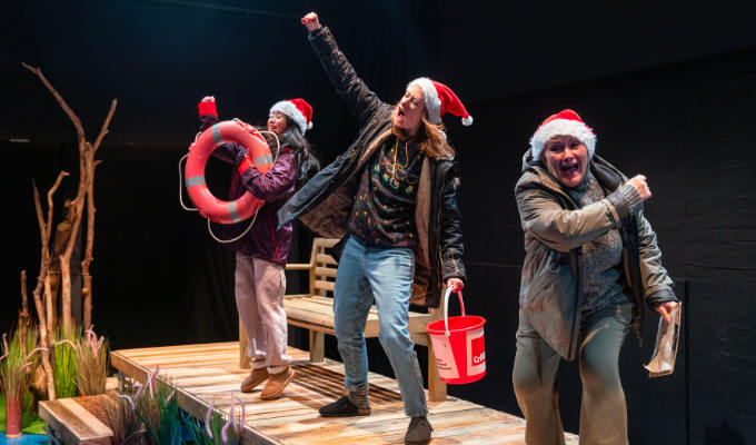 Three women on a jetty in Santa hats