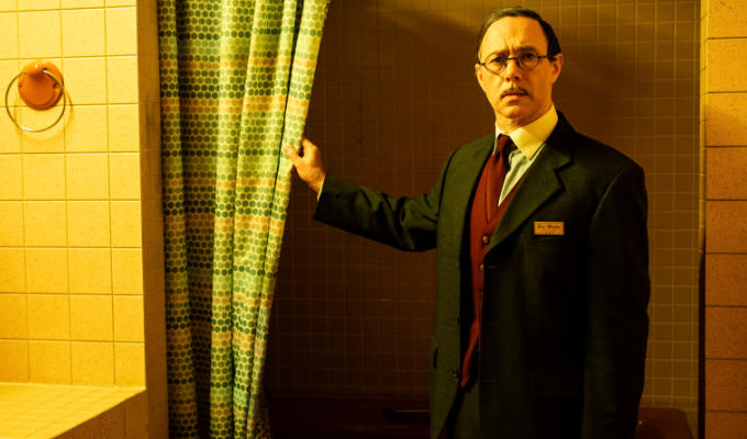 Shearsmith in hotel  bathroom pulling back shower curtain