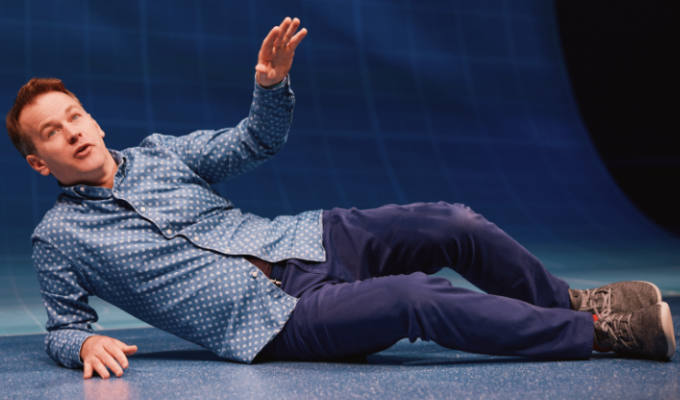 Birbiglia lying down on stage