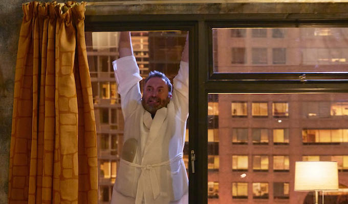 Mack hanging outside a hotel window in Not GOing Out