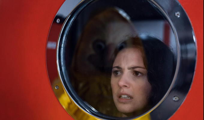 Scared looking woman at a porthole from Wrecked